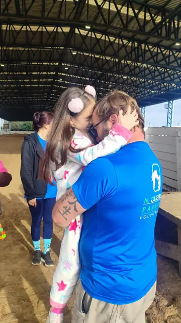 Criança abraçando um profissional da equipe