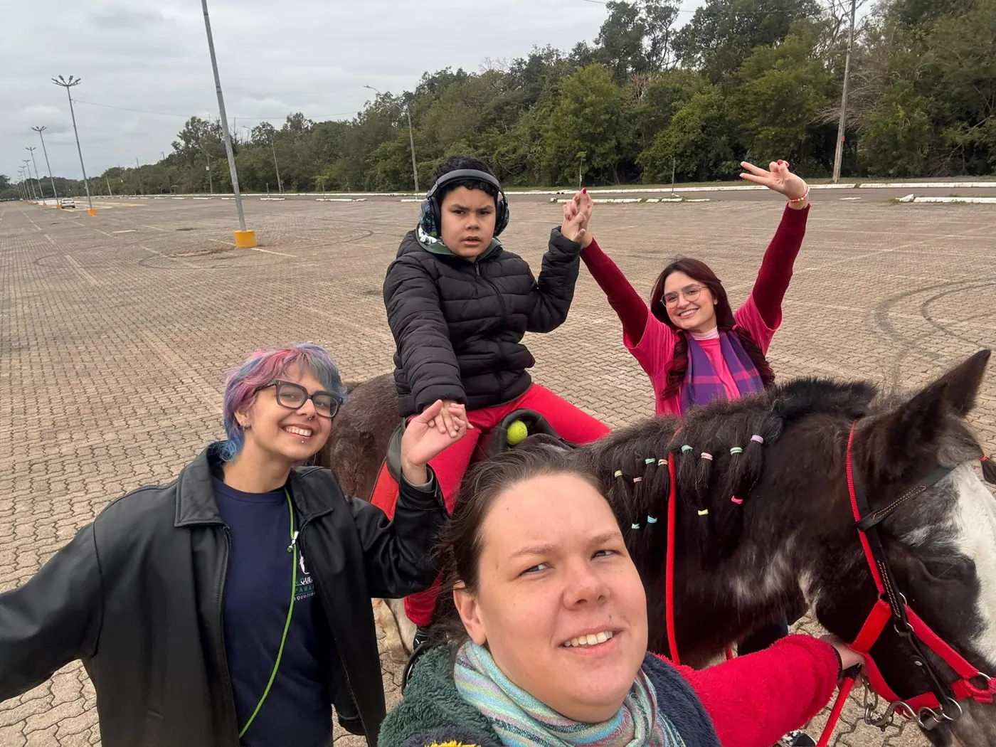 Equipe e praticantes sorrindo juntos, com um cavalo ao fundo